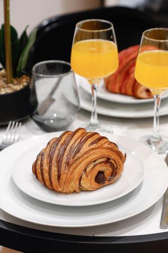 une assiette avec une viennoiserie sur une table et deux verres de jus d'orange dans l'établissement Leo Suite Cozy Studio, à Paris
