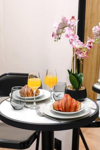 - une table avec deux verres de jus d'orange et des viennoiseries dans l'établissement Leo Suite Cozy Studio, à Paris