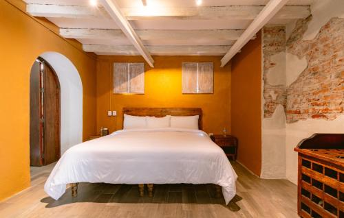 a bedroom with a white bed with orange walls at Casa Xaca in San Miguel de Allende