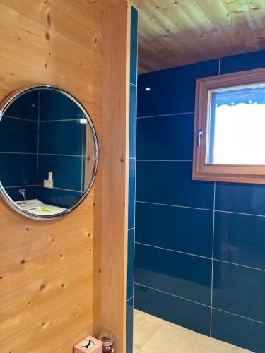 La salle de bains est pourvue d'un miroir et d'un mur bleu. dans l'établissement Small cottage, à Contamine-sur-Arve