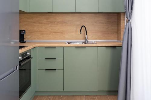 a kitchen with green cabinets and a sink at Flamingo Living Halkidiki - The Villas in Áyios Mámas