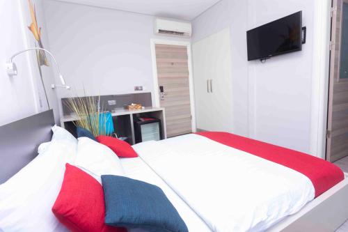 a bedroom with a bed with red and blue pillows at Urbano Hotel in Accra