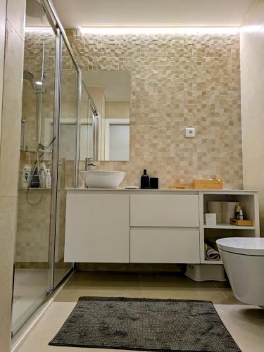 a bathroom with a sink and a toilet and a mirror at Porta da Praia - Paredes da Vitória in Senhora da Vitória