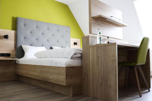 Schlafzimmer mit einem Bett, einem Schreibtisch und einer grünen Wand in der Unterkunft Wallfahrtswirt in Wemding