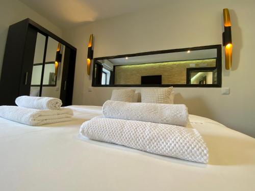 a bedroom with a bed with white sheets and a mirror at AL Barbinha in Faro