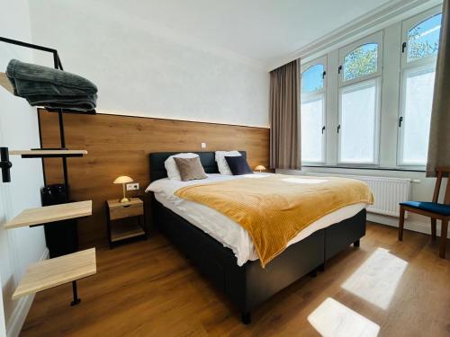 a bedroom with a large bed and two windows at Maison Jacqueline in Nieuwpoort