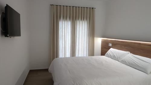 a bedroom with a white bed and a television at Kalea Elysivm in Alcalá del Júcar