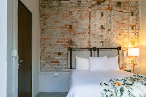 a bedroom with a white bed with a brick wall at Casa Xaca in San Miguel de Allende