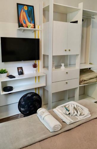 a living room with a tv and white cabinets at Studio compacto no Centro in Florianópolis