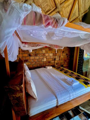 a bunk bed with white sheets on top of it at Masaka Cultural Resort in Masaka