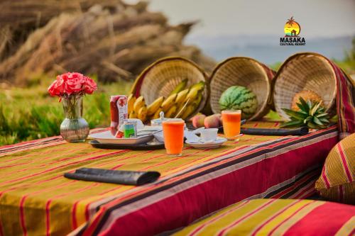 a table with a plate of food and fruit on it at Masaka Cultural Resort in Masaka
