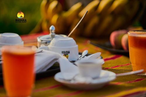 a table with a plate of food and a drink at Masaka Cultural Resort in Masaka