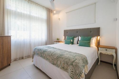 a bedroom with a large bed with green pillows at Coco Beach I - Seaside Home , Pool , Beach at 200 meters in Pointe aux Cannoniers