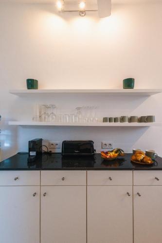 a kitchen with white cabinets and a black counter top at Coco Beach I - Seaside Home , Pool , Beach at 200 meters in Pointe aux Cannoniers