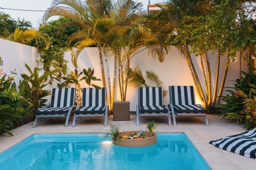 two chairs sitting next to a swimming pool with palm trees at Coco Beach I - Seaside Home , Pool , Beach at 200 meters in Pointe aux Cannoniers