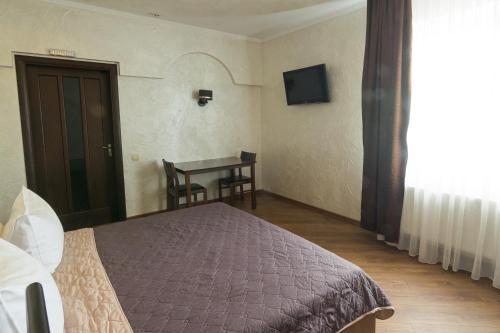 a bedroom with a bed and a table with a television at Шахерезада in Vinnytsya