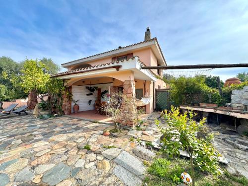 a small pink house with a stone patio at Colori di Sardegna Apartments in Bari Sardo