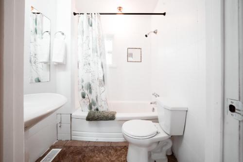 a white bathroom with a toilet and a tub and a sink at Stay & Play - Central Family Friendly in Calgary