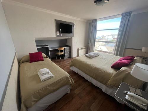 two beds in a hotel room with a window at Gran Hotel Laserre in Río Grande