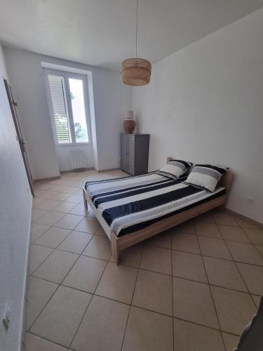 une chambre avec un lit dans une pièce blanche dans l'établissement Appartement 1 chambre, à Sartène