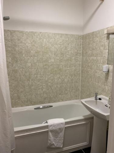 a bathroom with a sink and a bath tub and a sink at The Brentwood Hotel Porthcawl in Porthcawl