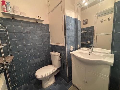 La salle de bains est pourvue de carrelage bleu, de toilettes et d'un lavabo. dans l'établissement Studio à côté du Marché Couverts, à Le Touquet-Paris-Plage