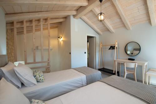 una camera da letto con due letti, un tavolo e uno specchio di Villa Iliana a Gaios