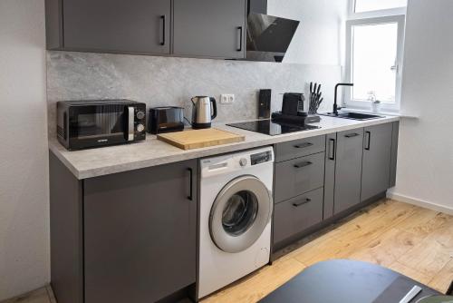 a kitchen with a washing machine and a microwave at hygge-flats Apartment für 2-6, WLAN, Homeoffice in Heppenheim an der Bergstrasse