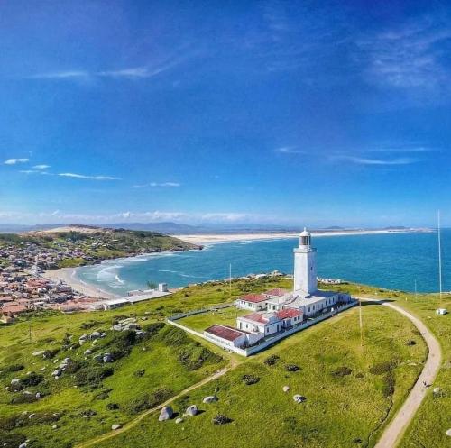 a lighthouse on a hill next to a body of water at Resid. Clube Mar Grosso - Laguna - LAG201 in Laguna