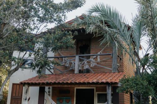 a brick house with a balcony and palm trees at Recanto Pitanga in Vale do Capao