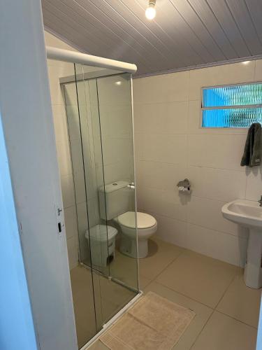 a bathroom with a toilet and a glass shower at Casa Oceano, Ilha do Mel in Paranaguá