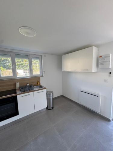 une cuisine avec des armoires blanches et un four à plaques de cuisson dans l'établissement Grand T2 rénové Cœur de St-Priest Avec Parking, à Saint-Priest