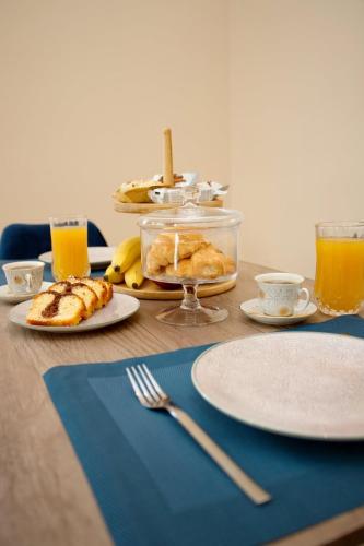 a wooden table with plates of food and orange juice at Skyway Comfort Residences in Spáta