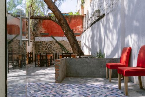 a patio with two red chairs and a tree at Casa Xaca in San Miguel de Allende