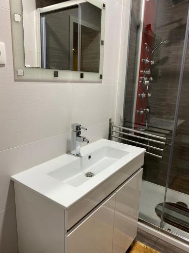 a white bathroom with a sink and a shower at Nature & Family Guesthouse in Louredo
