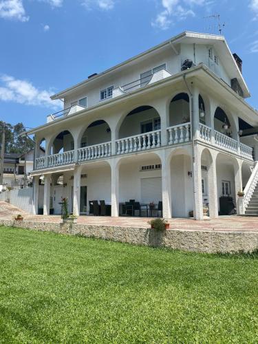 a large white house with a lawn in front of it at Nature & Family Guesthouse in Louredo