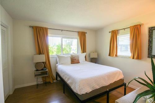 a bedroom with a bed and two windows with orange curtains at Beautiful 3 BR pool home minutes from Siesta Key - Blue Dolphin in Sarasota