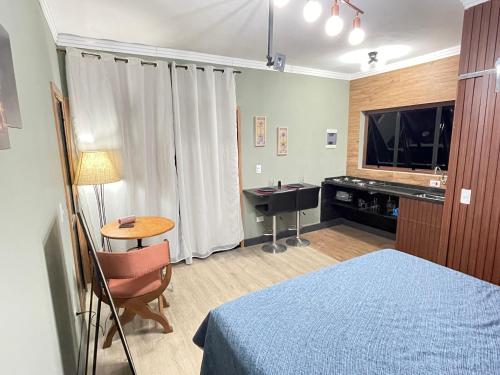 a bedroom with a bed and a desk and a television at Topázio in São Pedro