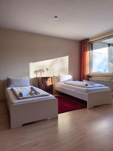 a bedroom with two beds and a table and a window at Monteurwohnung Osnabrück 3-Zimmer mit Balkon in Osnabrück