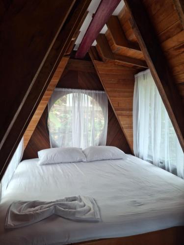 a bed in a attic with a window at Cabaña Alamo frente al mar in Capurganá
