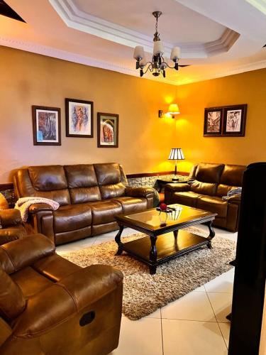 a living room with brown leather couches and a table at Meru Havens in Arusha