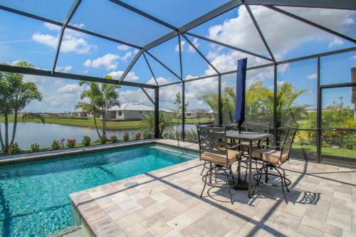 a patio with a table and chairs next to a swimming pool at Serene lakefront pool home in Lorraine Lakes - Coral Paradise in Bradenton