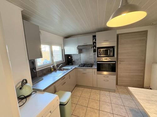 a large kitchen with white cabinets and a ceiling at Horse House Calm and Nature near motorway and Basel in Kembs