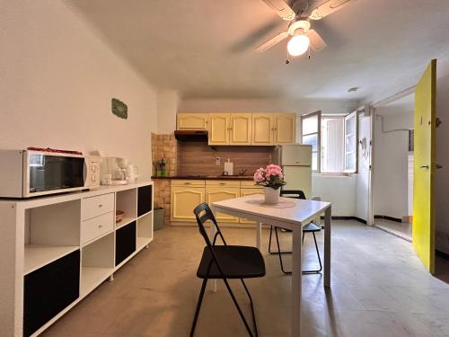 une cuisine avec une table avec des chaises et un micro-ondes dans l'établissement Studio Tournesol au pied des Arènes, à Arles
