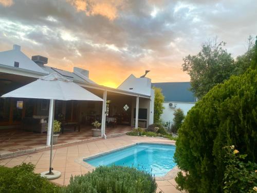 a house with a swimming pool and an umbrella at Karoo Escape 2 in Oudtshoorn