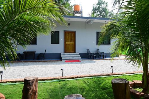 a white house with a front yard with palm trees at George's Legacy Stay in Kāsarkod