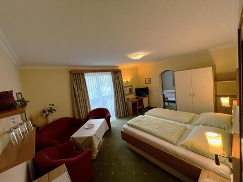 a hotel room with a large bed and a chair at Pension Schlömmer in Sankt Gilgen