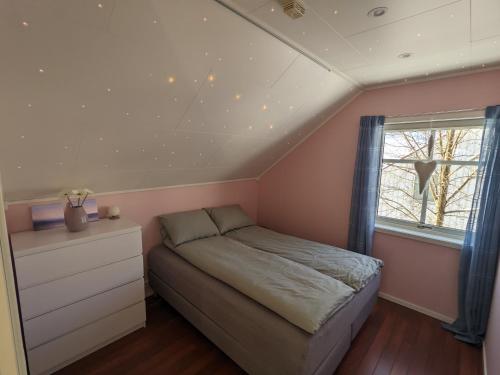 a small bedroom with a bed and a window at Loftsleilighet,havutsikt,balkong,gratis parkering in Tromsø