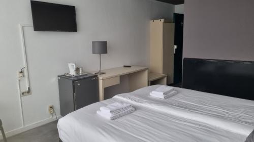 a bedroom with a bed with two folded towels on it at City Hotel Winschoten in Winschoten