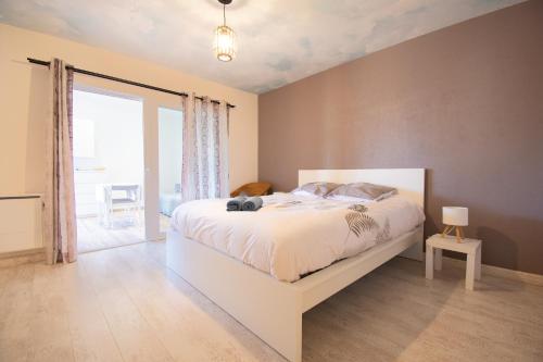 a bedroom with a white bed and a large window at Le Petit Moulin I Plage et terrasse in Crozon